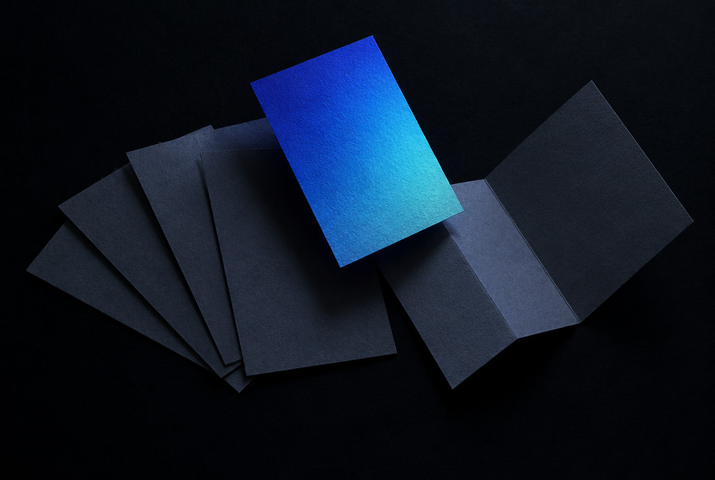 Abstract still of loose paper cards and a folded diagram arranged on a pale surface